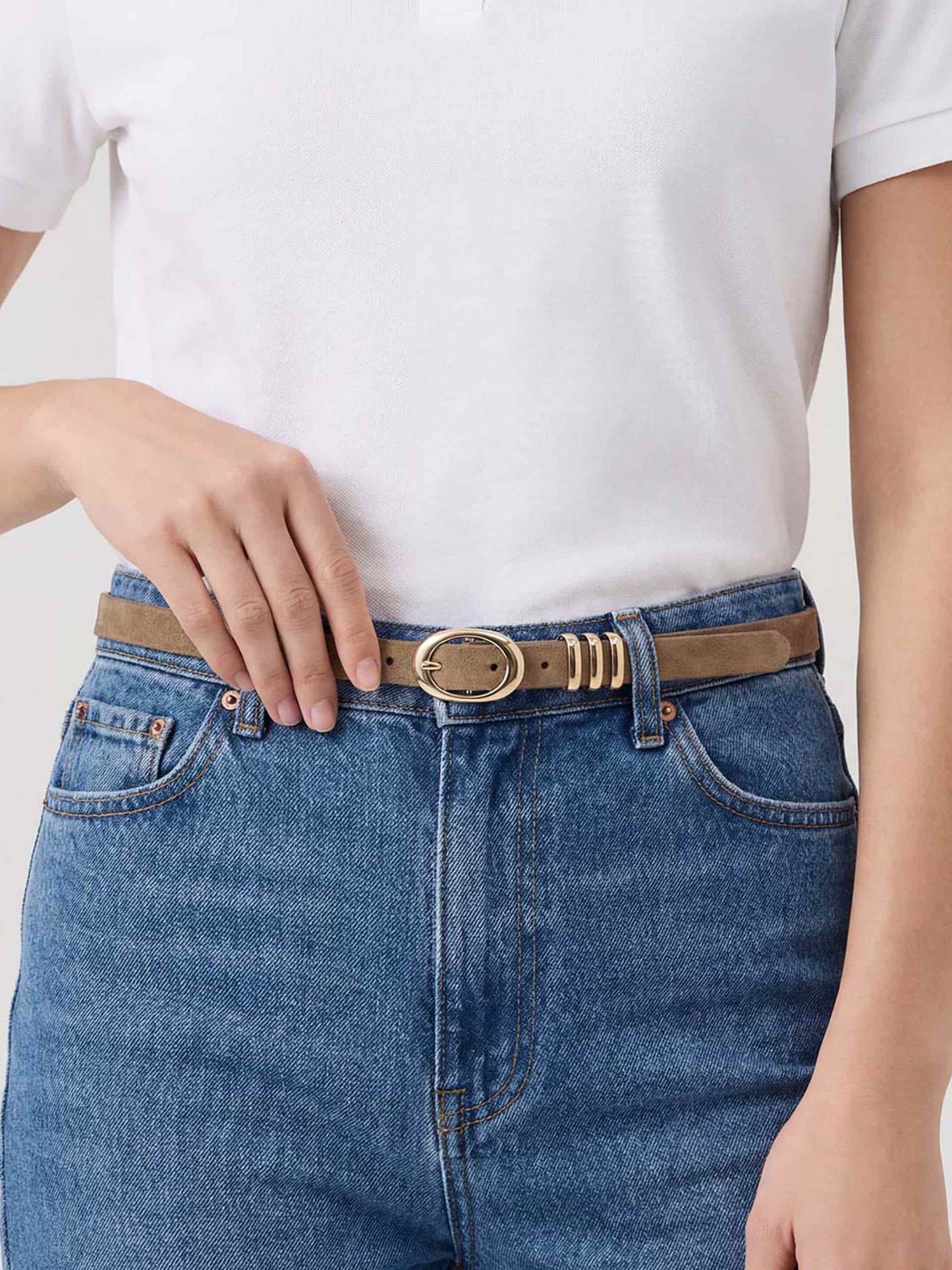 Close-up of shiitake-colored belt with oval buckle and gold accents on blue jeans