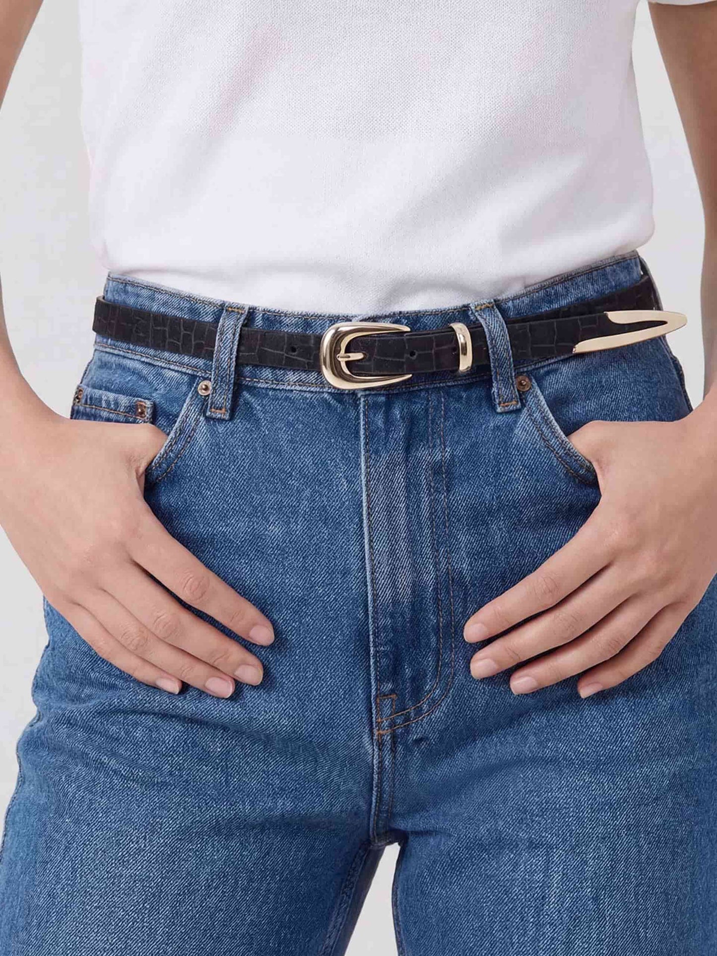 Front view of black belt with gold buckle worn with blue jeans and tucked white tee