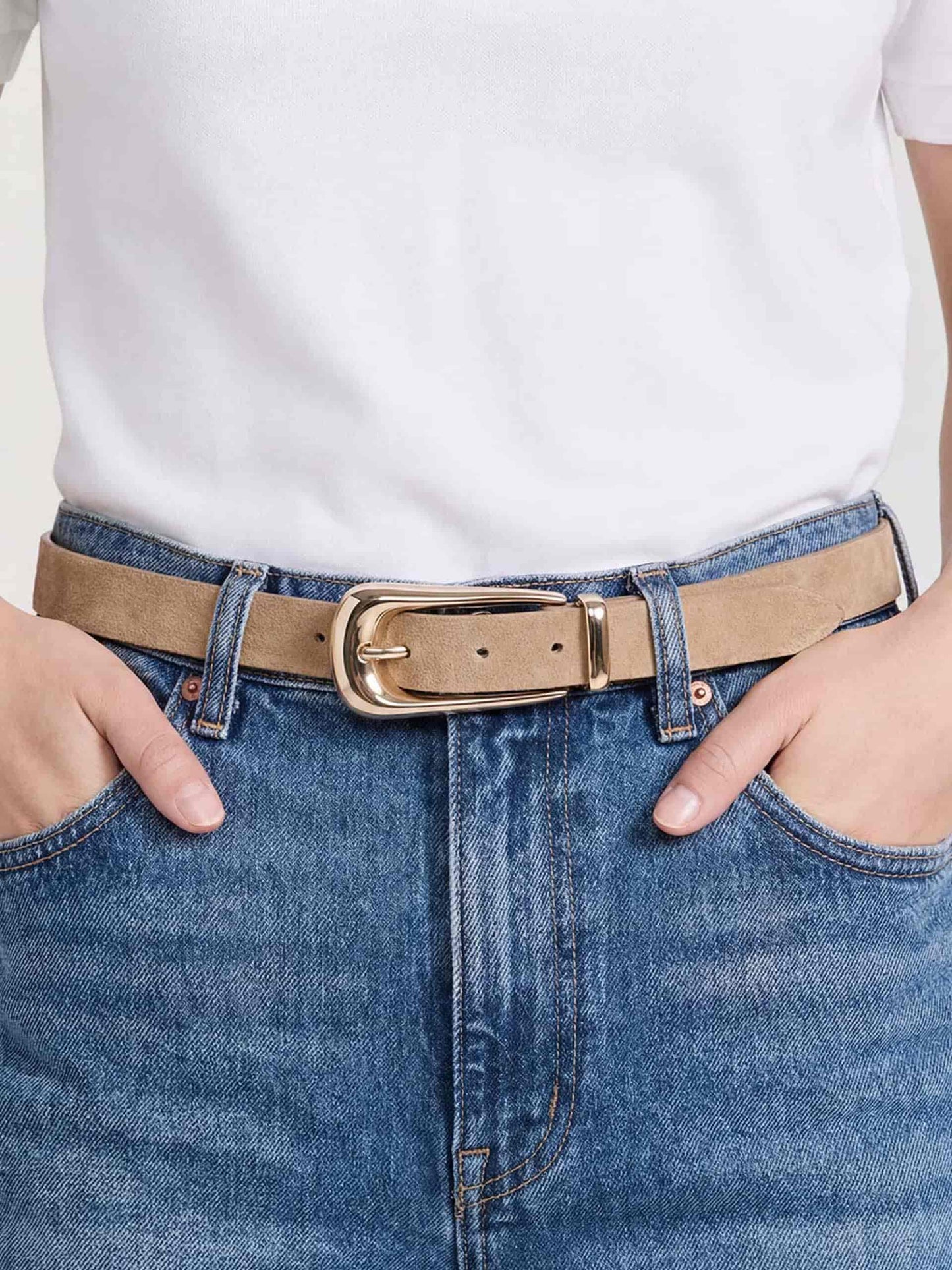 Close-up of Shiitake leather belt with gold buckle, paired with white shirt and blue jeans.