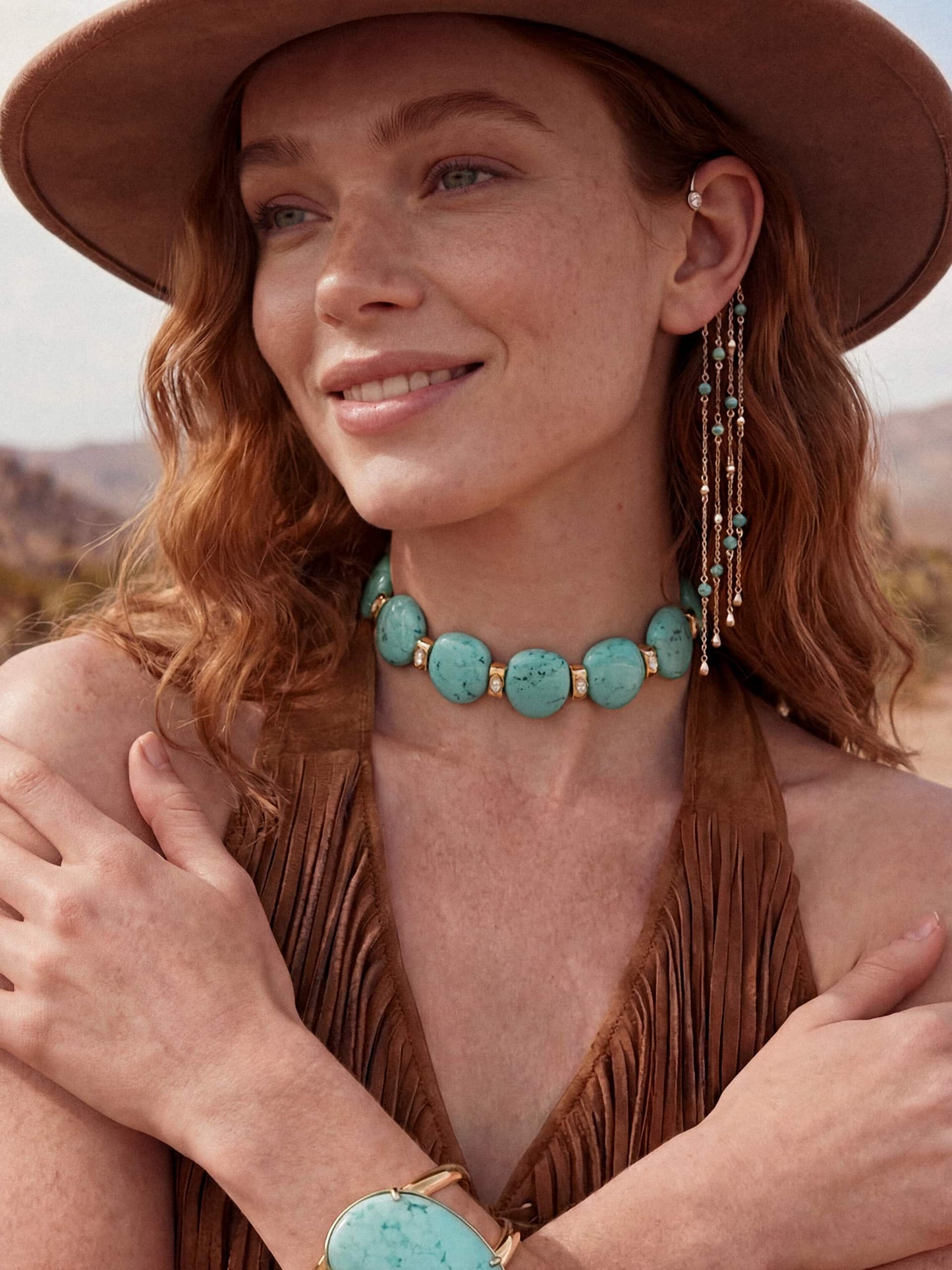 Model wearing turquoise stone choker necklace and matching bracelet, styled with brown fringe top and hat outdoors.