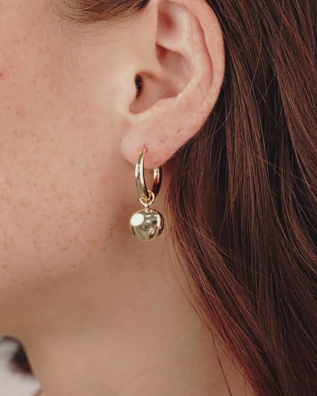 Polished Pebble Huggie Hoop Earrings in gold on model in video