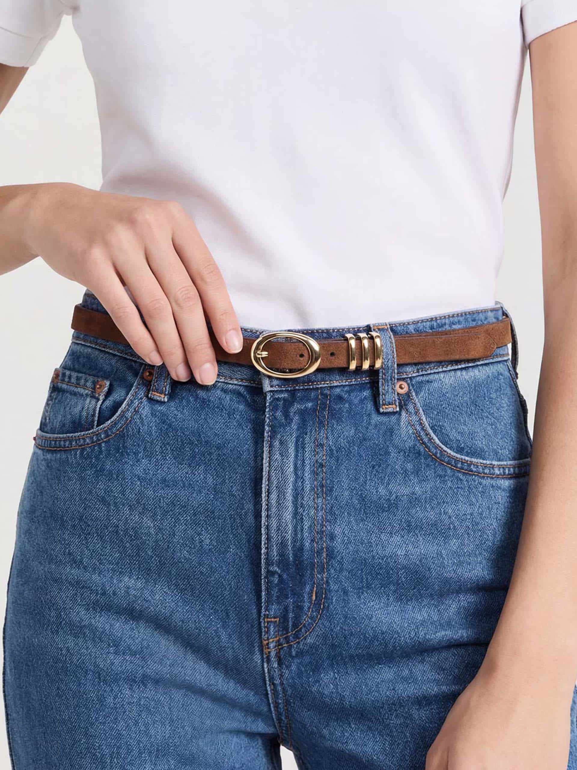 Close-up of brown belt with gold details styled on high-waisted blue jeans