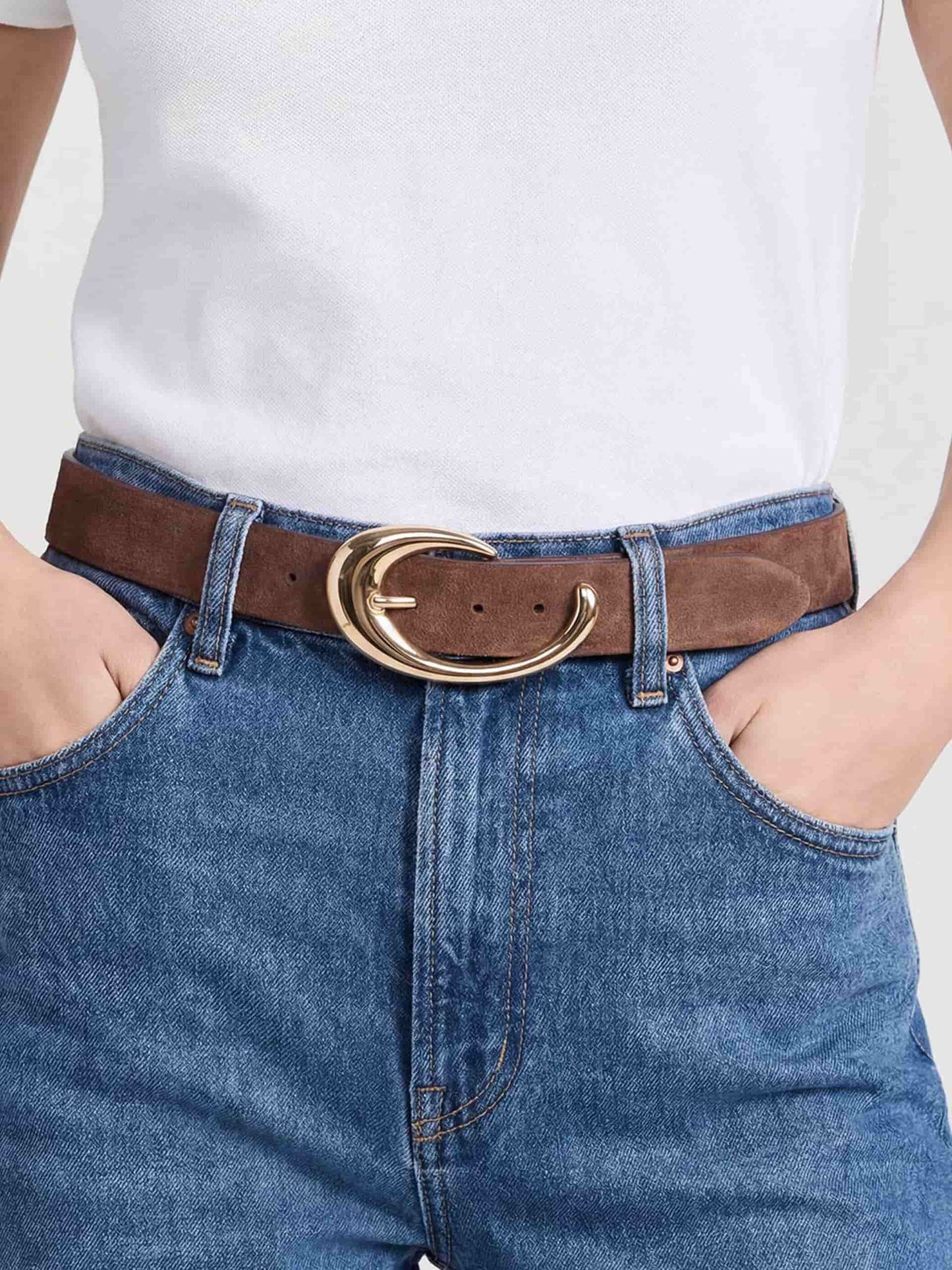 Tan belt with gold oval buckle styled with denim jeans.