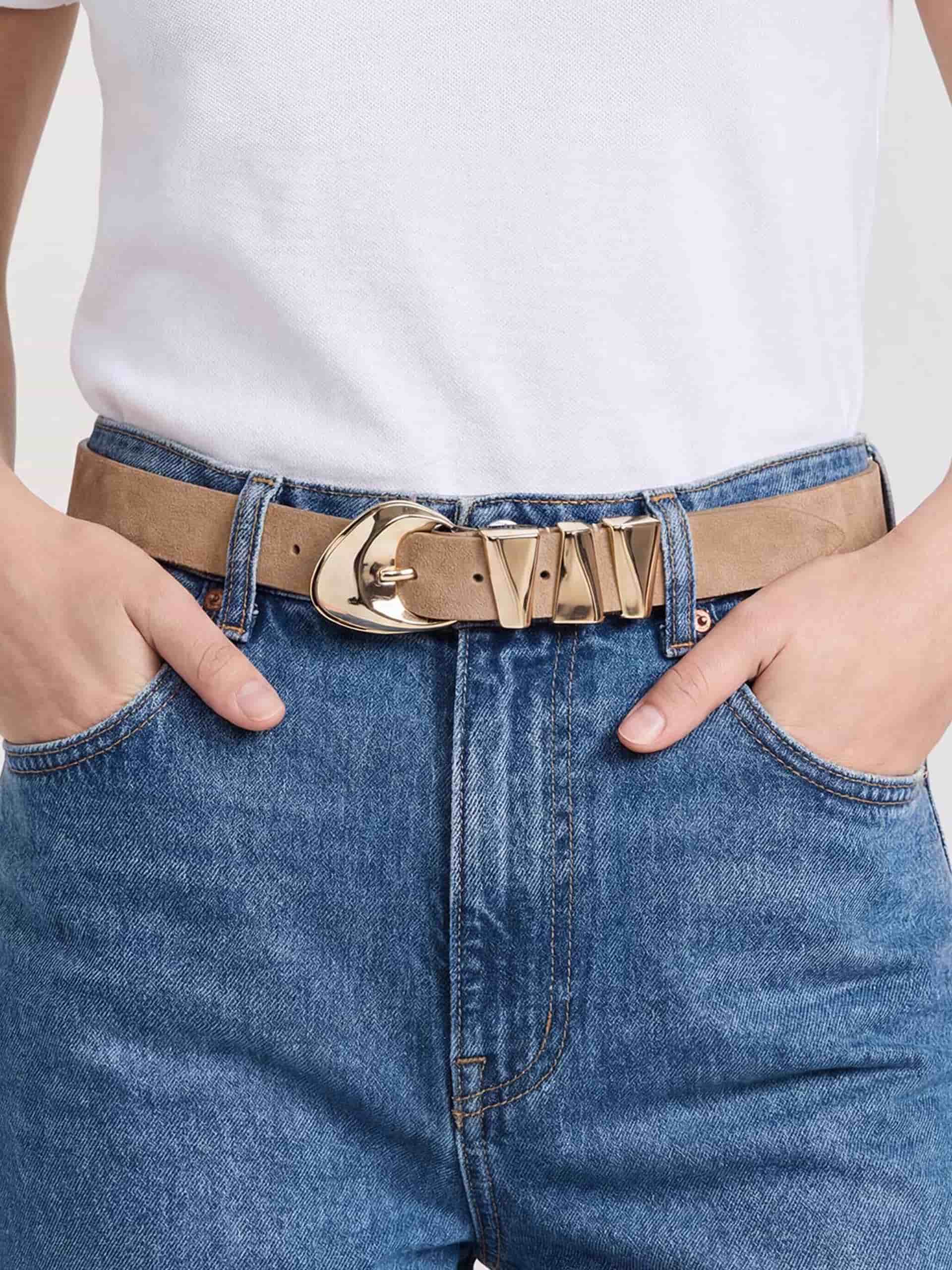 Skinny gold belt with wrap buckle styled with denim jeans.