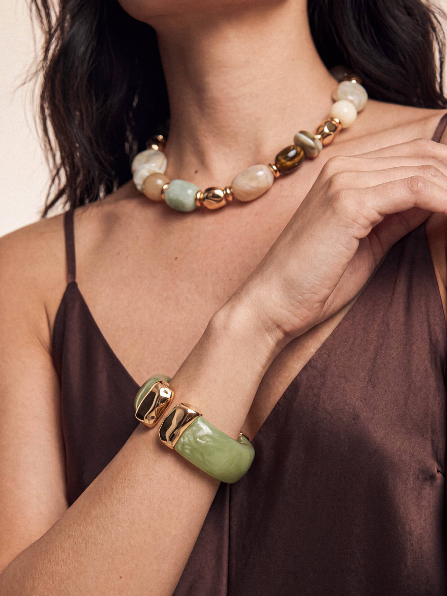Model highlighting beaded necklace and green stone bracelet