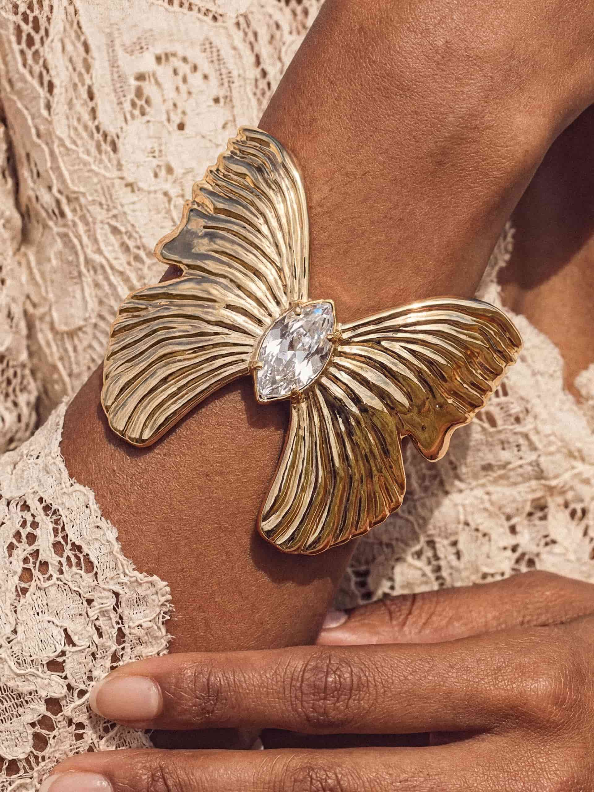 Gold butterfly cuff with crystal pendant on woman in white lace