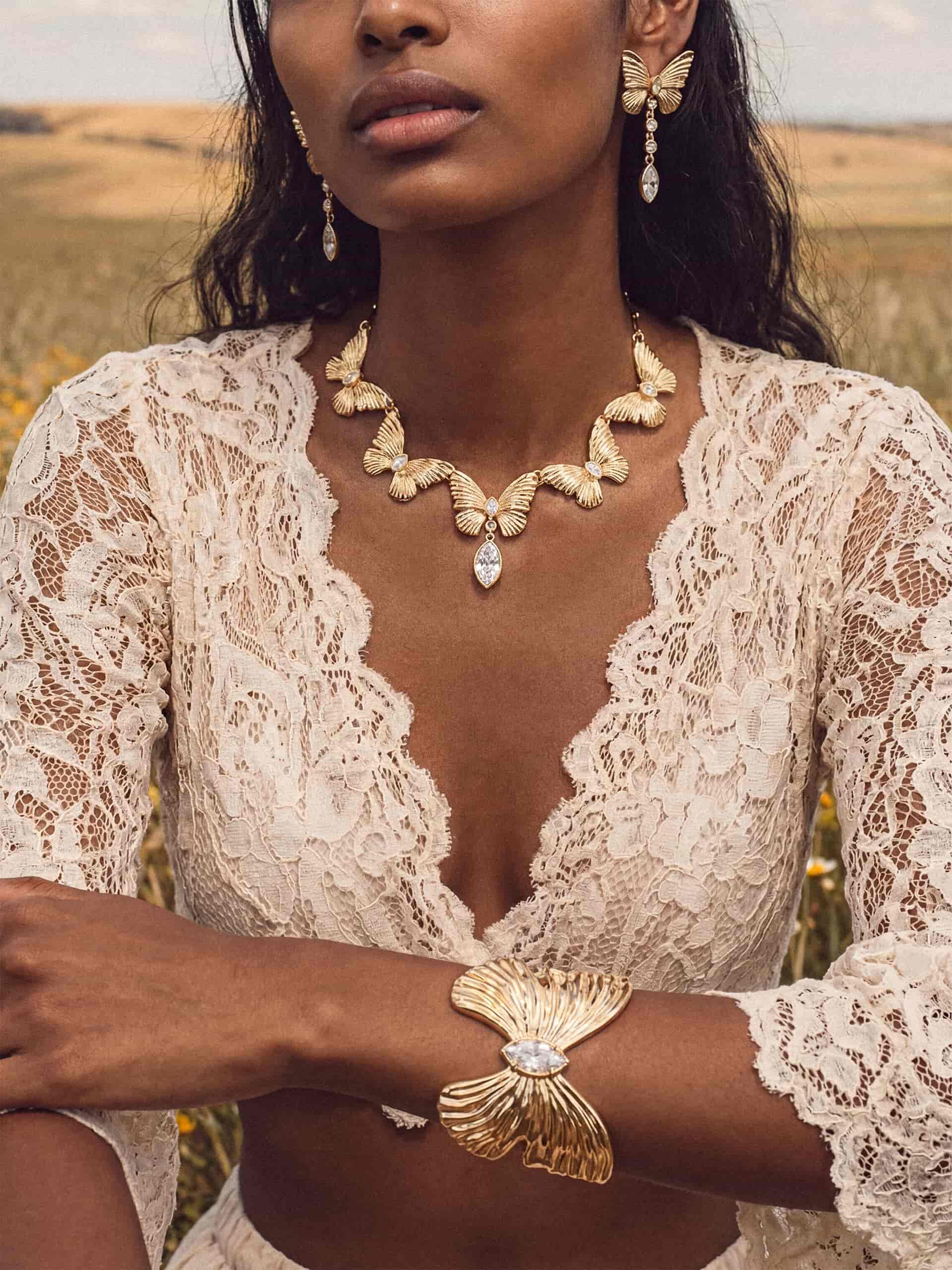 Gold butterfly jewelry set with crystal pendant on woman in white lace
