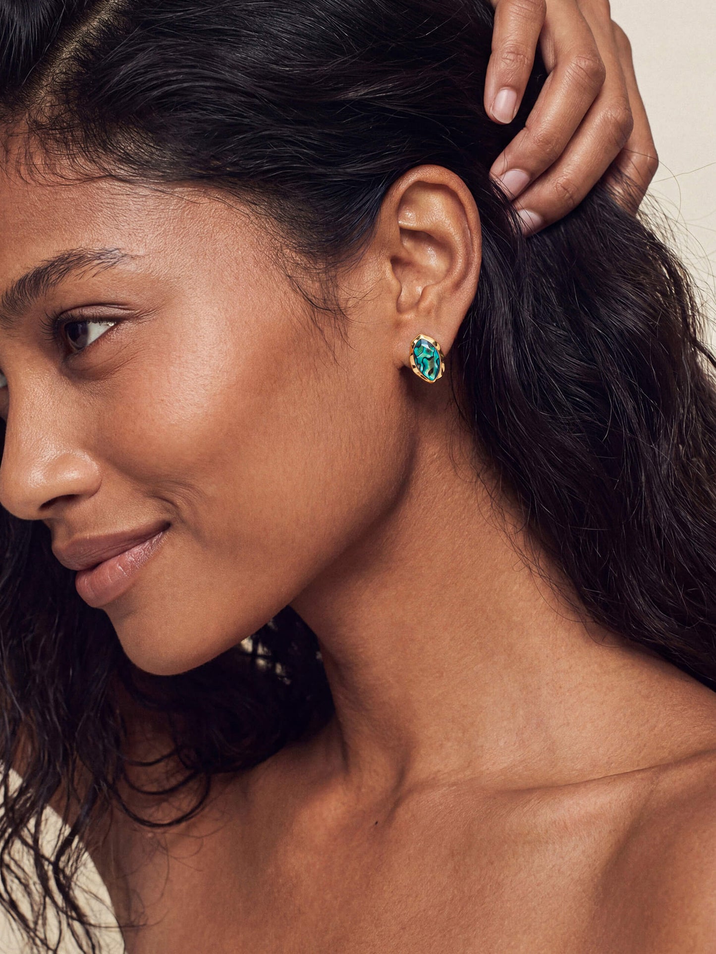 Model wearing a gold-framed abalone luxe shell earring with vivid iridescent blues and greens, conveying elegance and style.