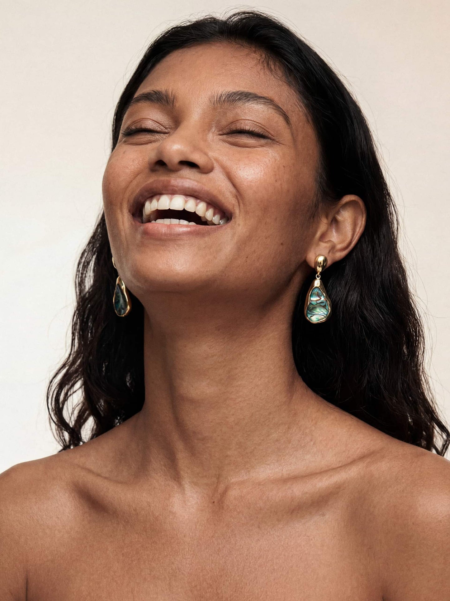 Model wearing a dangling Hidden Gem Abalone Earring with an abalone shell encased in gold. 