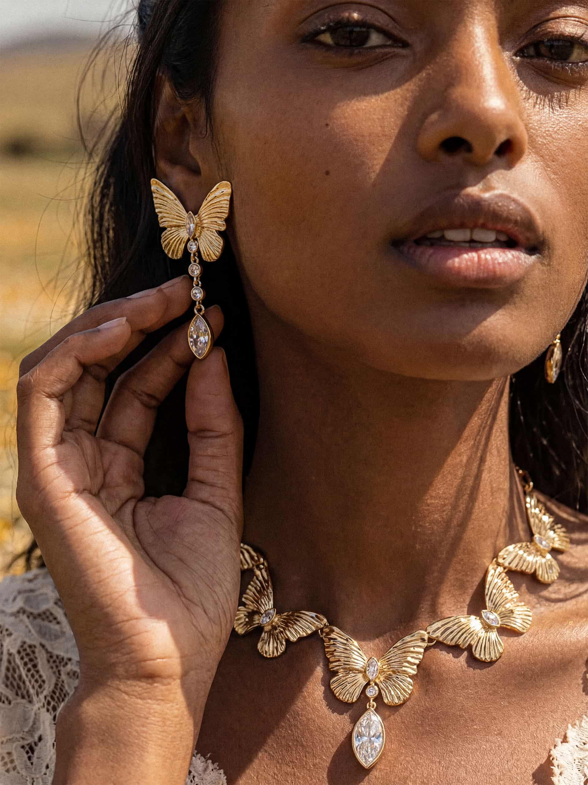 Woman wearing gold butterfly earrings and necklace