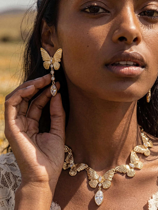 Woman wearing gold butterfly earrings and necklace