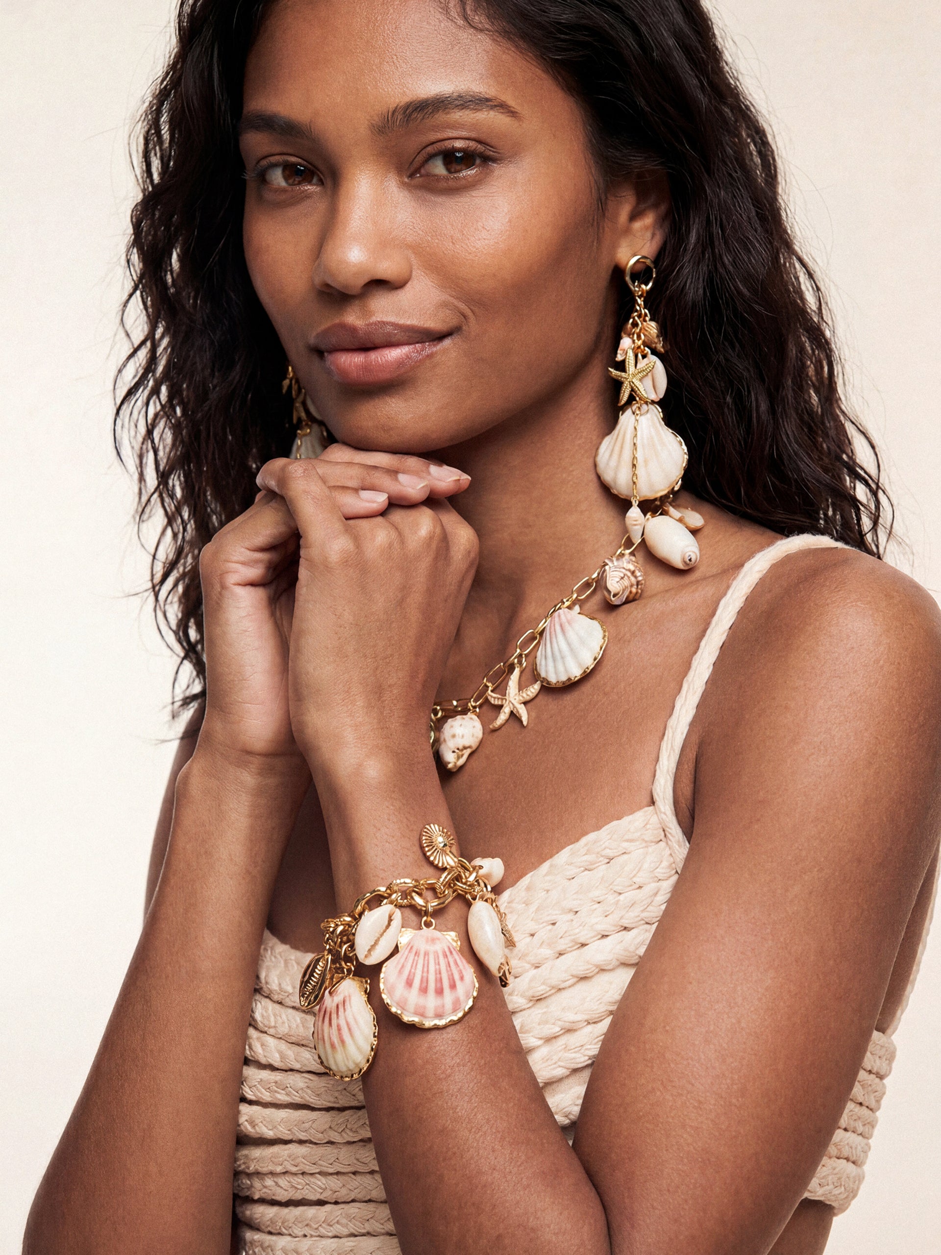 Model wearing Private Island Assorted Shell charm necklace, matching Mermaid Tears drop earrings and bracelet with neutral knit top