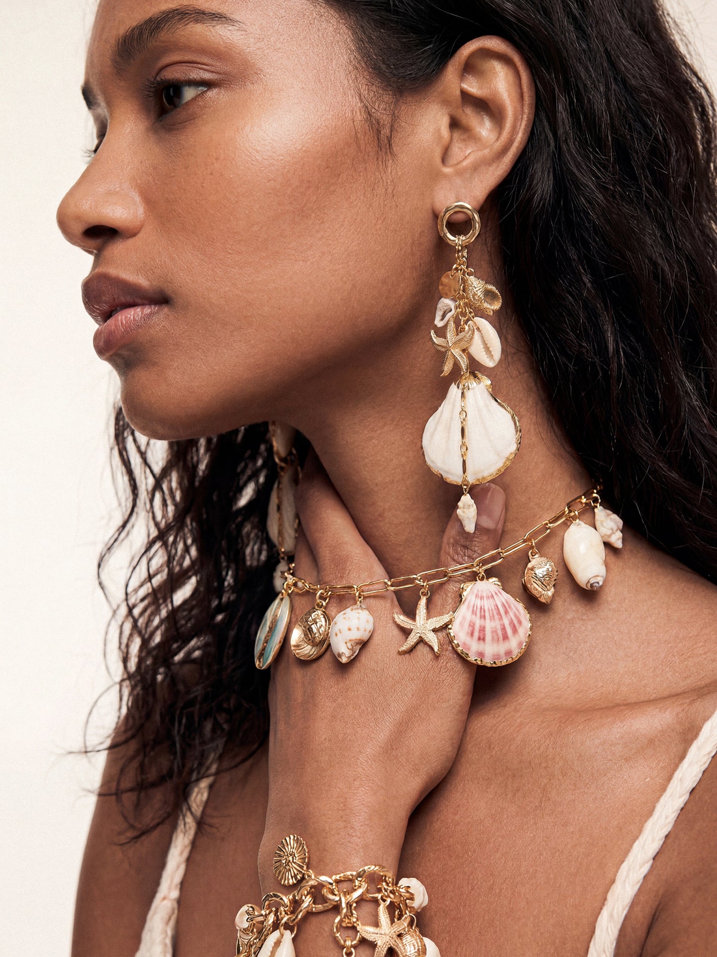 Model wearing elegant and beach-inspired shell necklace and dangling Mermaid Tears shell earrings and bracelet