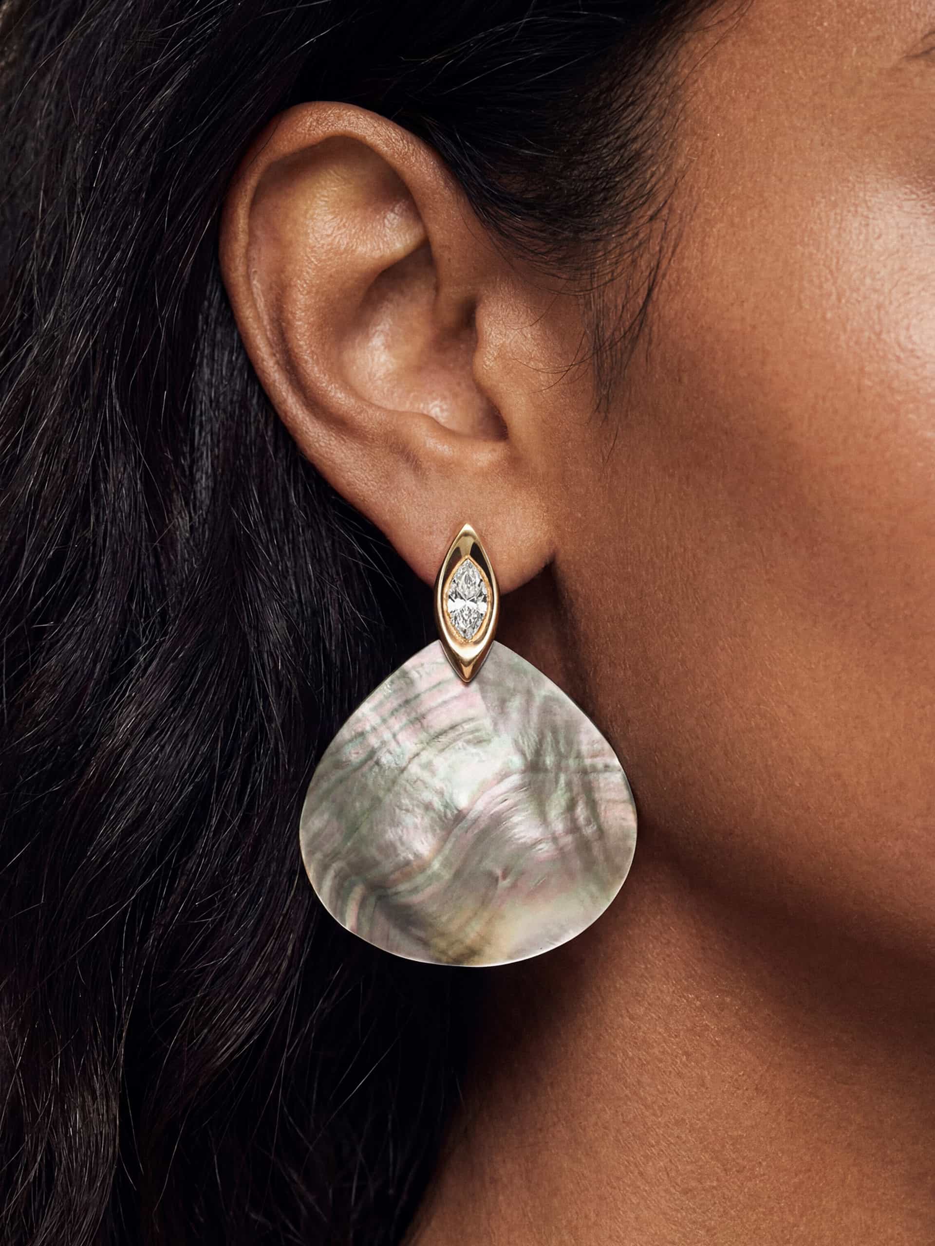 A large real shell earring with a shiny crystal in a teardrop-shaped gold