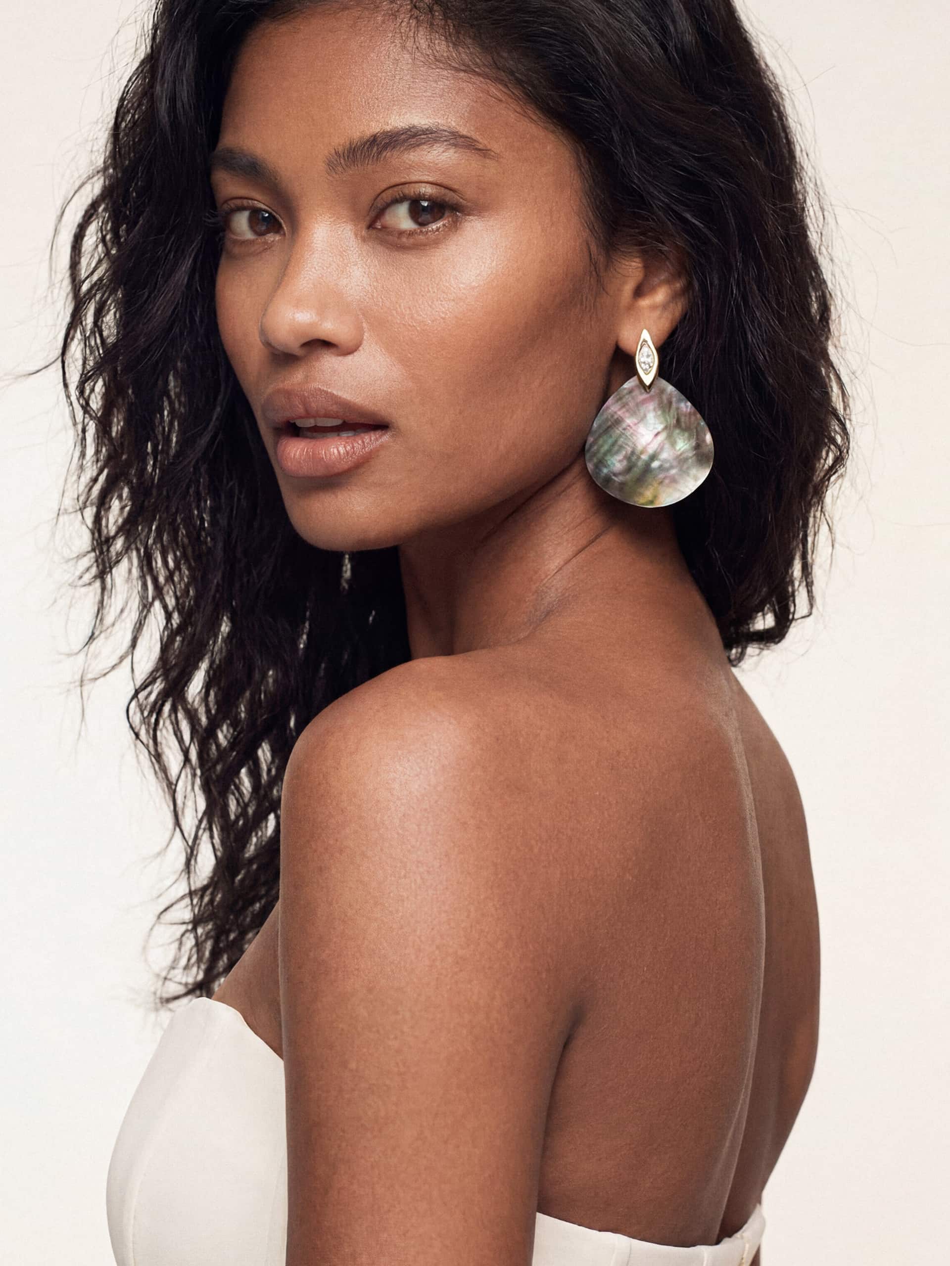 Model wearing bold, shell statement earrings and a strapless top, exuding elegance.