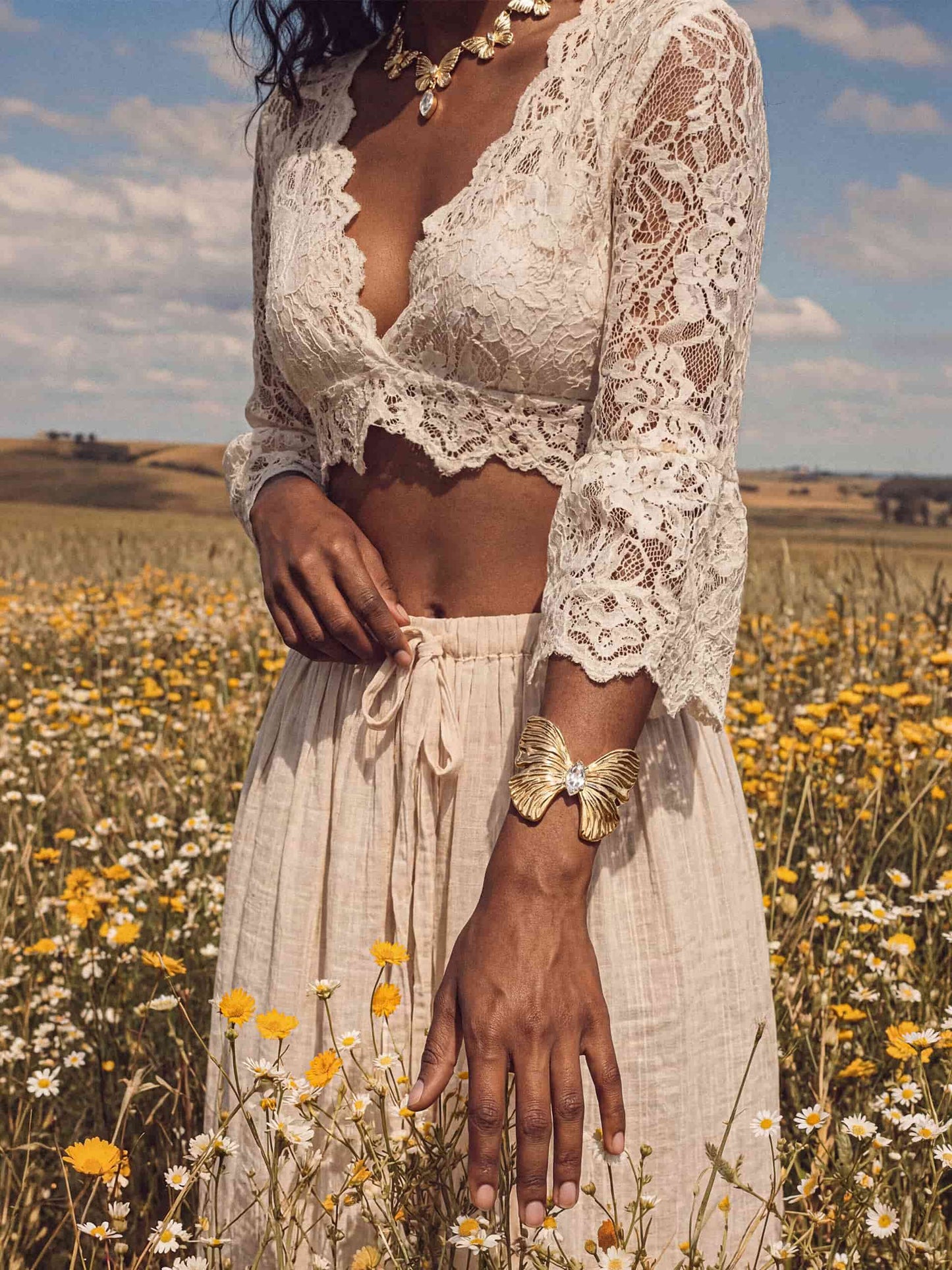 Gold butterfly cuff and choker with crystal pendant on woman in white lace