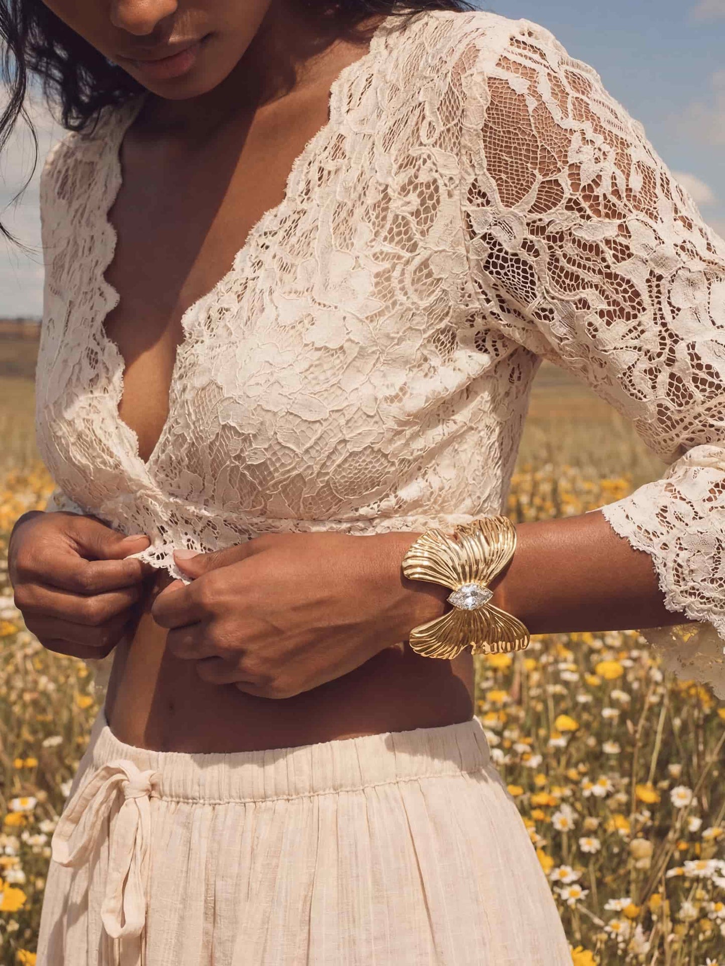 Gold butterfly cuff with crystal pendant on woman in white lace