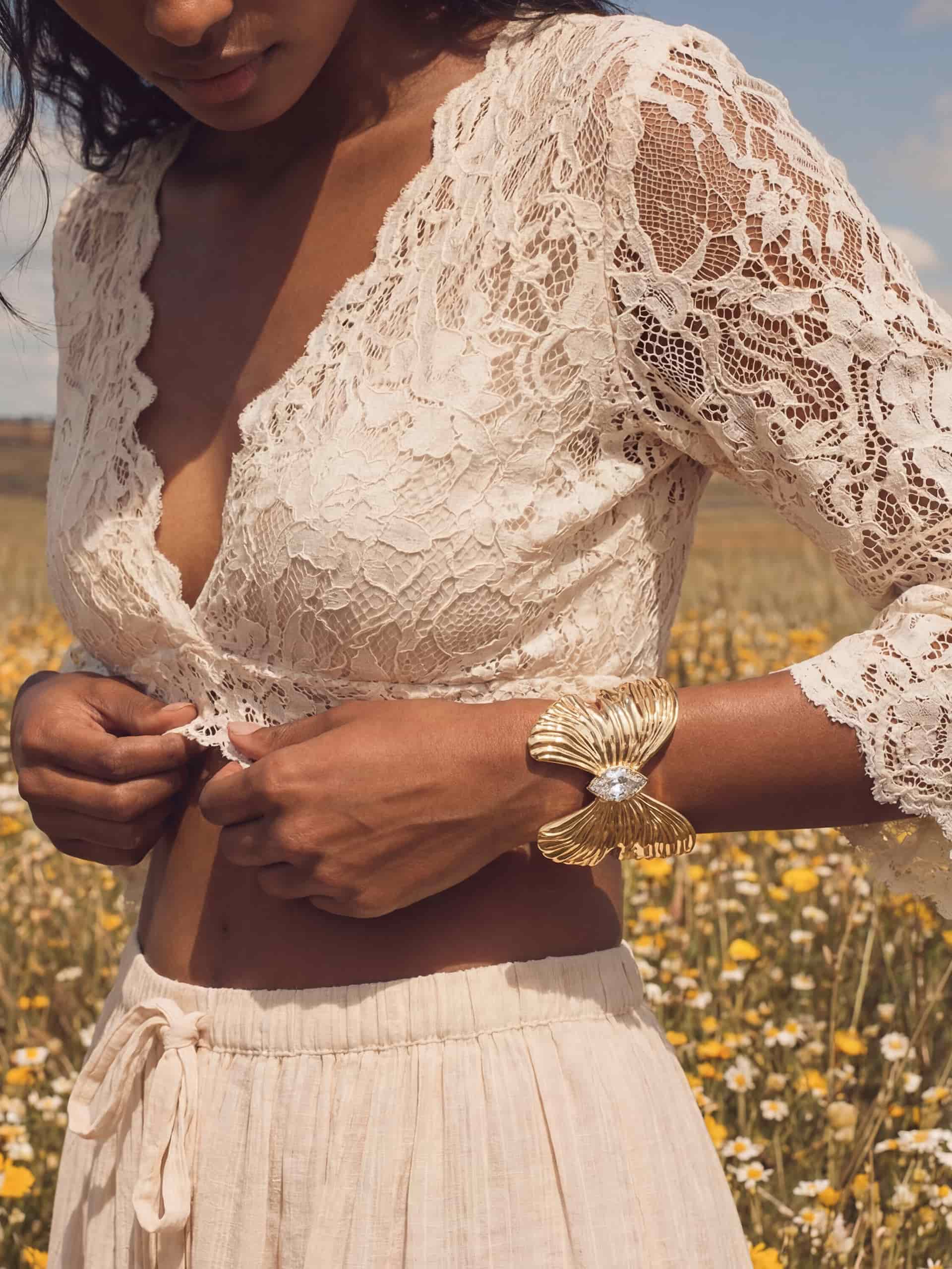 Gold butterfly cuff with crystal pendant on woman in white lace