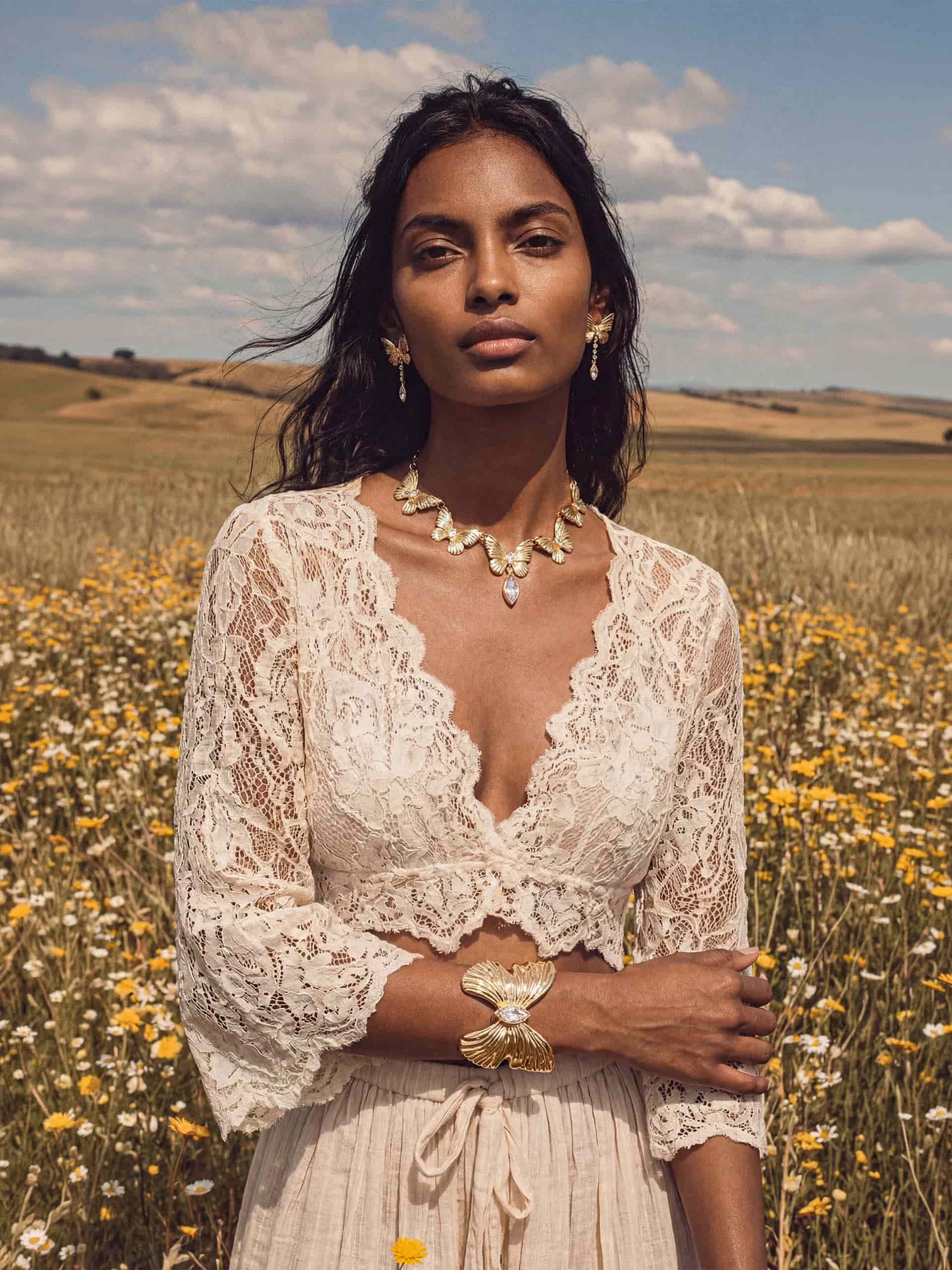 Model in white lace maxi dress with gold butterfly jewelry