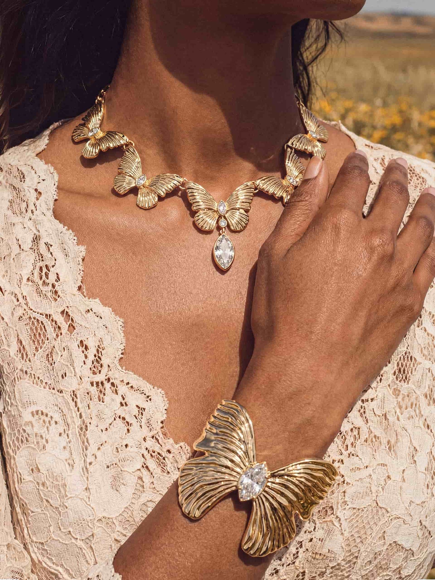Gold butterfly cuff and crystal necklace  on woman in white lace dress