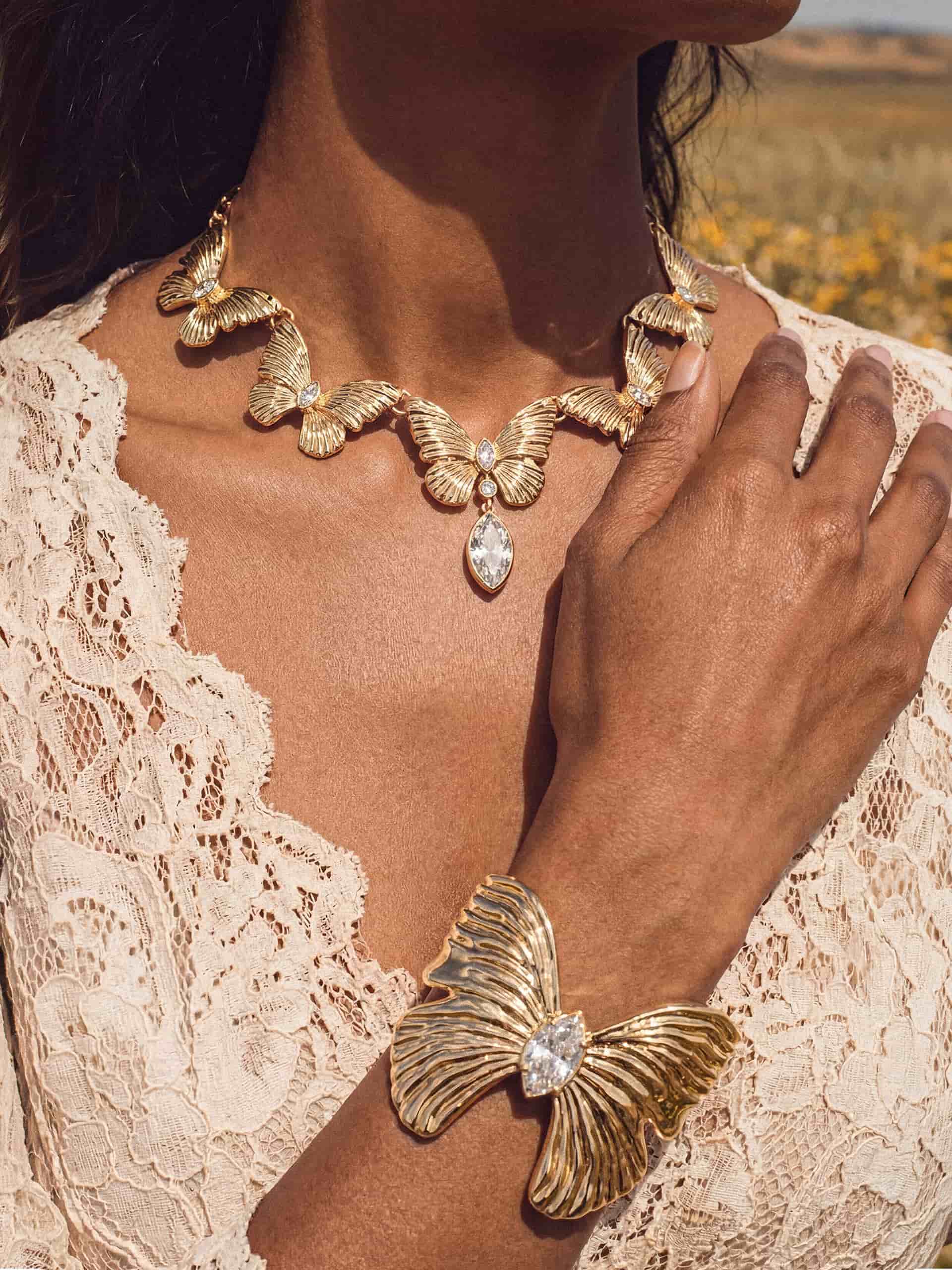 Gold butterfly cuff and crystal necklace  on woman in white lace dress