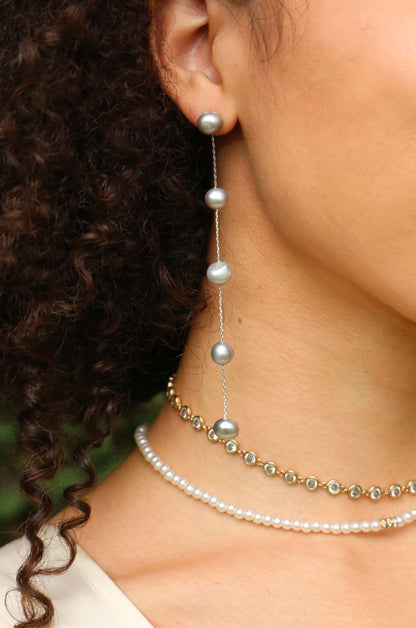 Dripping Pearl Delicate Drop Earrings in rhodium and gray on slate on a model