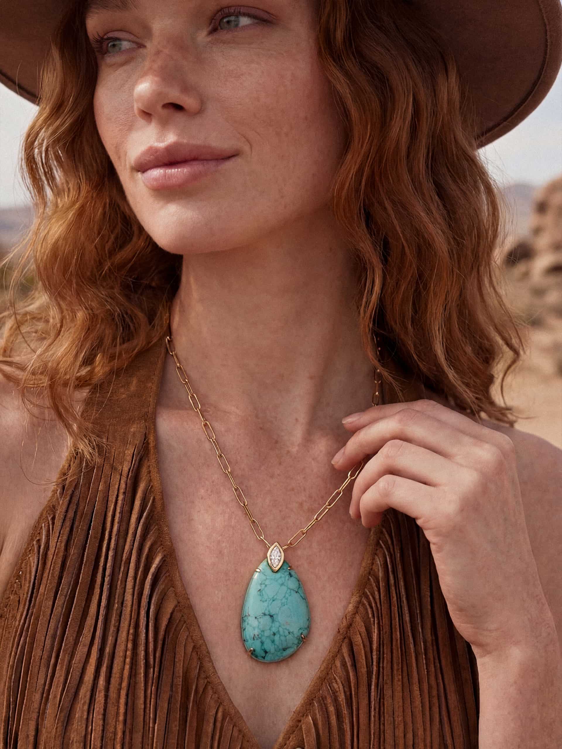 Model wearing turquoise pendant necklace and hat