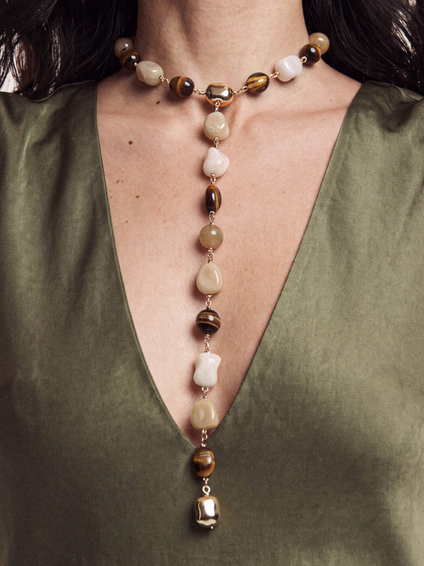Detailed view of mixed-stone beaded pendant necklace on green satin dress