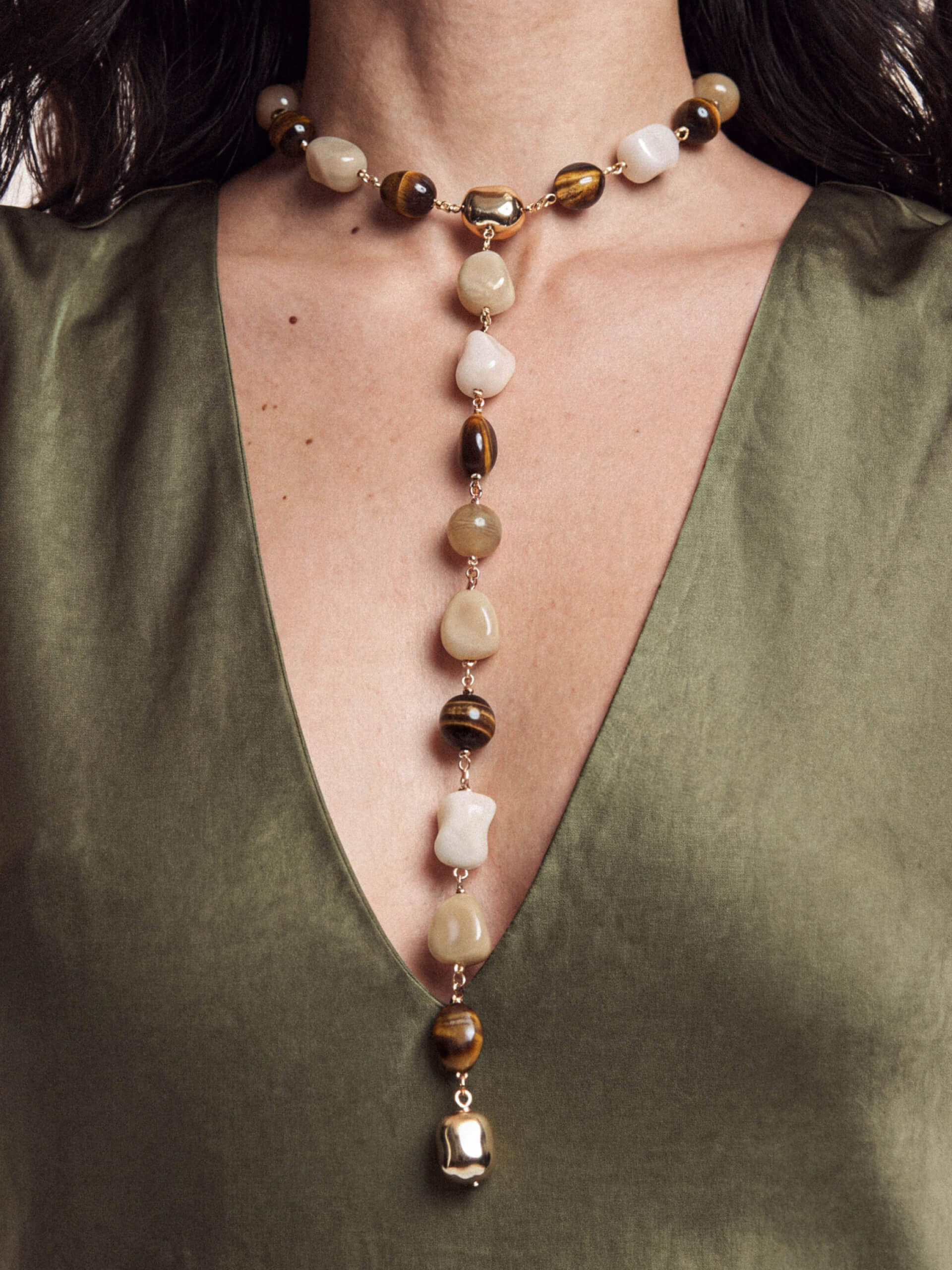 Detailed view of mixed-stone beaded pendant necklace on green satin dress