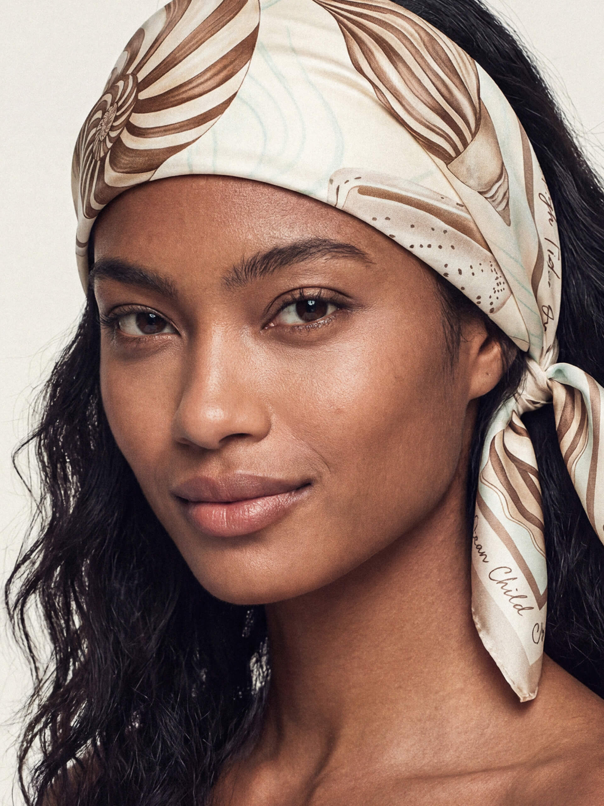 A woman wears a shell-patterned beige and brown headscarf. 
