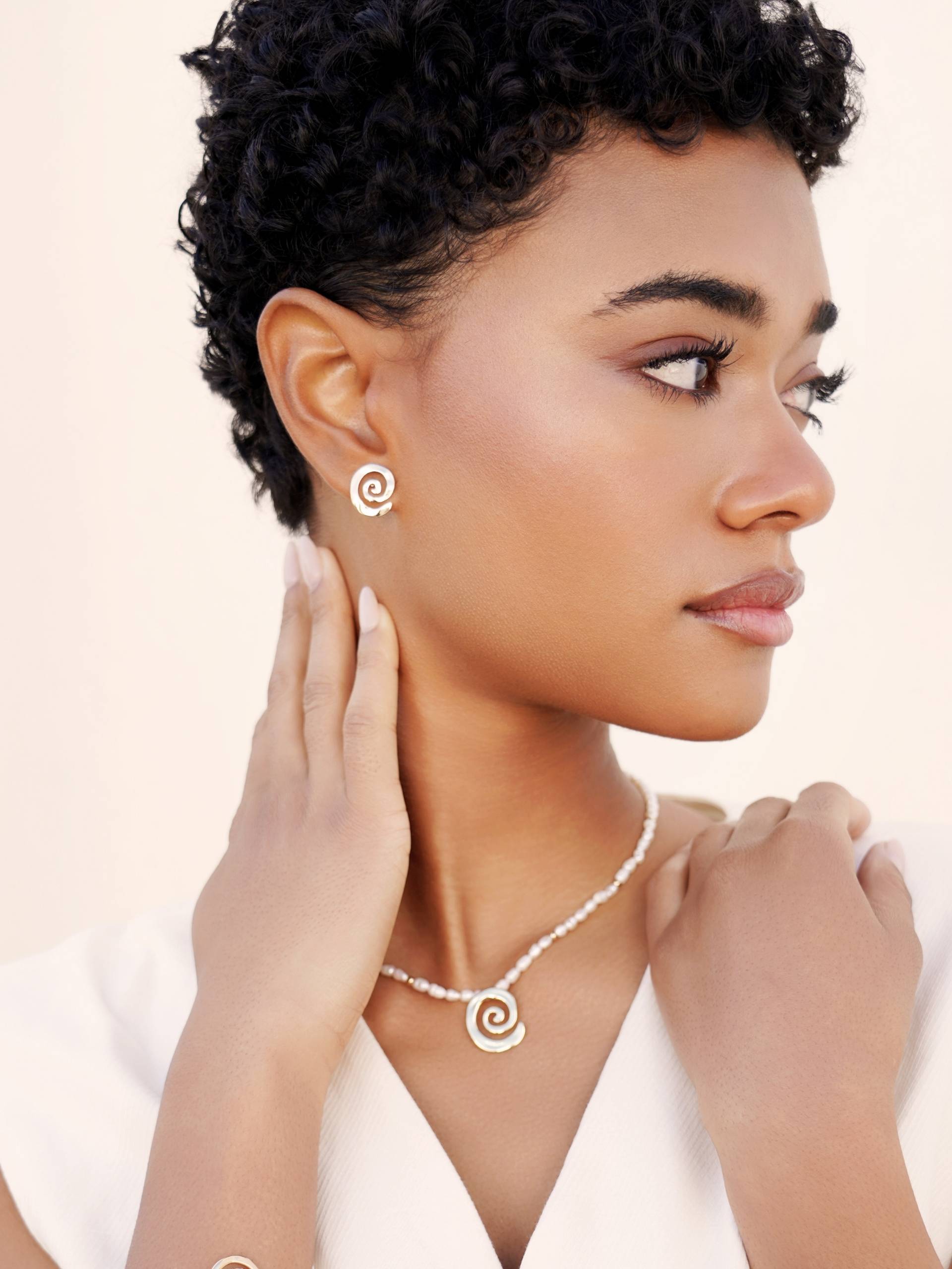 Woman wearing a necklace and earrings with a neutral background