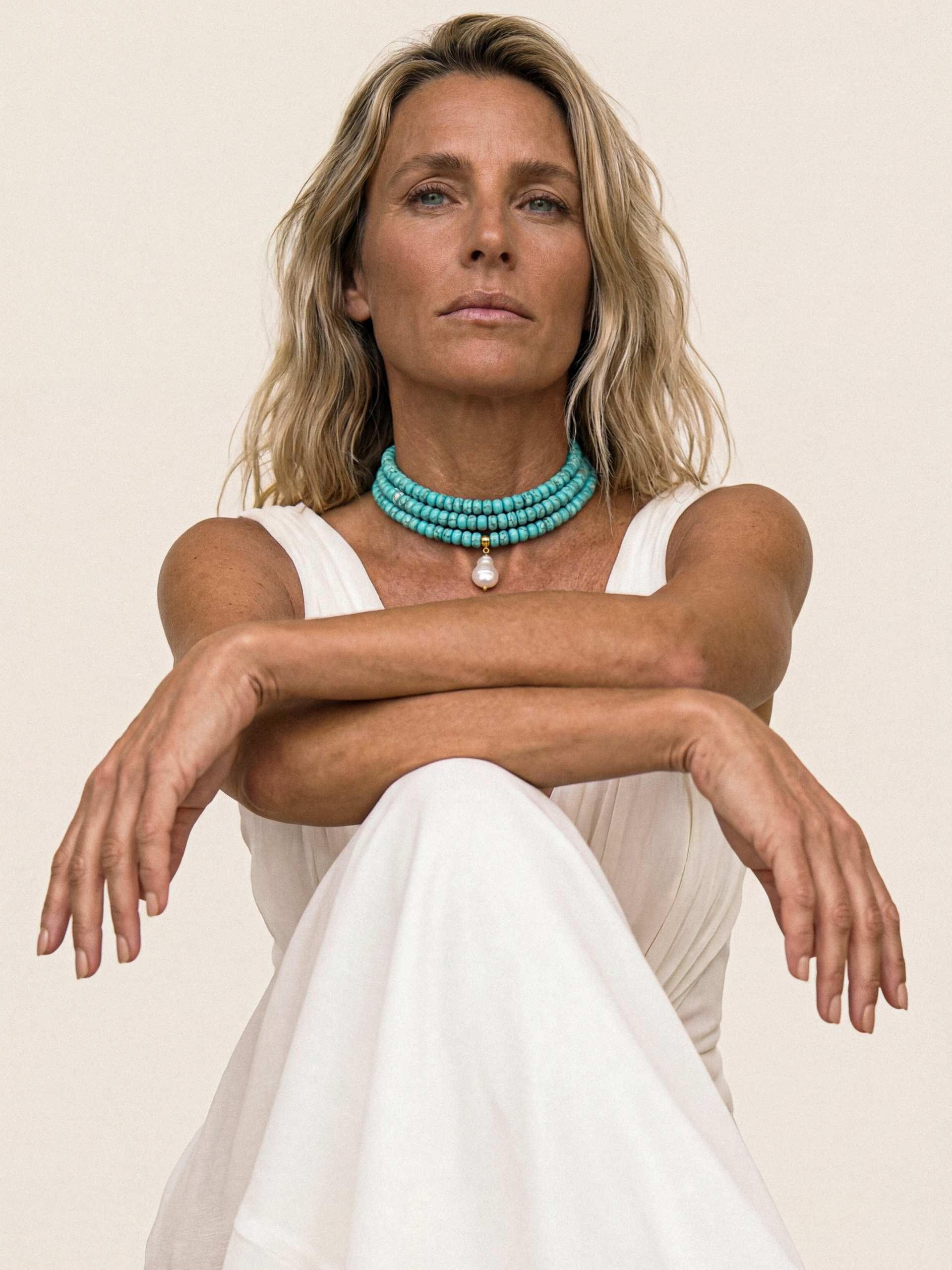 three layer beaded necklace on model crossing her arms over her lap