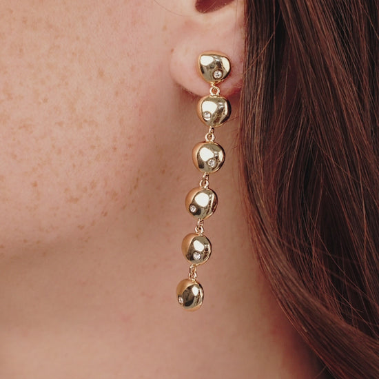 Polished Pebble Linear Dangle Earrings in gold on model in video