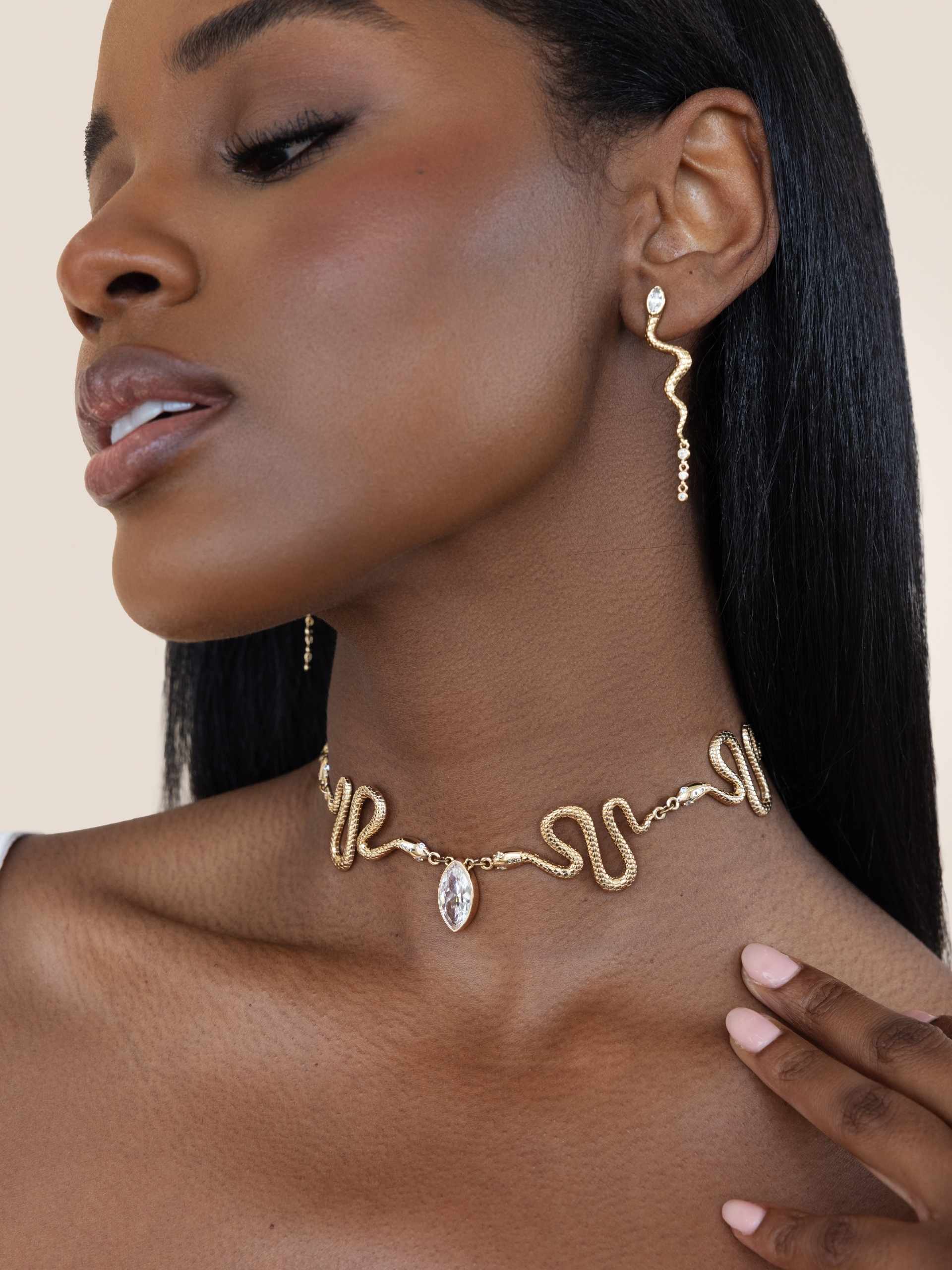 Woman wearing gold necklace and earrings on a beige background