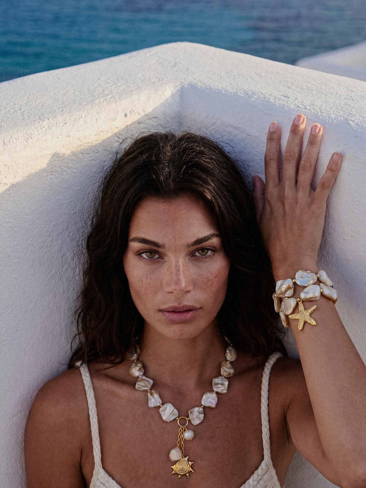Woman with jewelry against a white wall and blue background